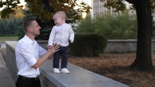 Smiling Toddler Taking First Steps with Adult Assistance