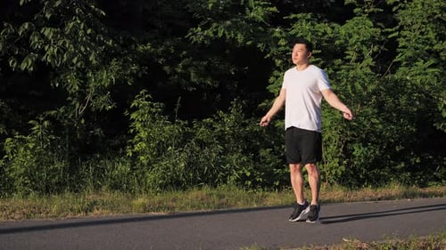 Man Jumping Rope Outdoors on Asphalt Path