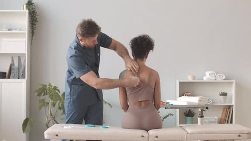 Man Applies Kinesiology Tape to Patient's Neck
