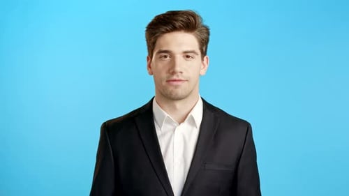 Portrait of Young Successful Confident Businessman Isolated on Blue Studio Background. Man in