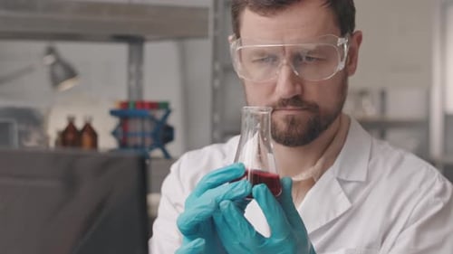 Scientist Analyzing Red Liquid in Flask in Laboratory