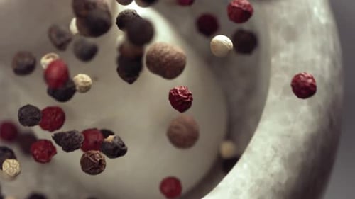 Peppercorns Falling Into a White Mortar