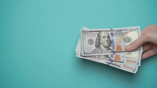 Hand passing US Dollar Bills