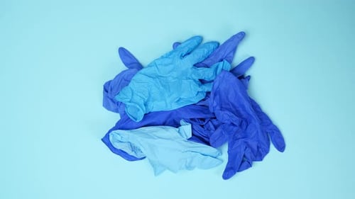 Hands Place Medical Gloves on Blue Surface