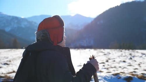Side View of Young Hiker Going Nordic Walking with Sticks on Snowy Trail in Field at Mountain
