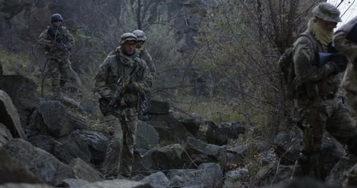 Bewaffnete Soldaten gehen in der Dämmerung durch Felsen