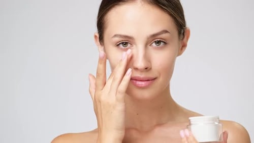 Young Woman Applies Moisturizer to Face