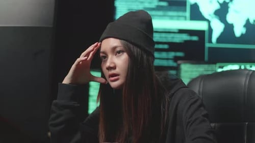 Une jeune femme asiatique qui s'ennuie utilise le piratage informatique et code sur plusieurs écrans d'ordinateur