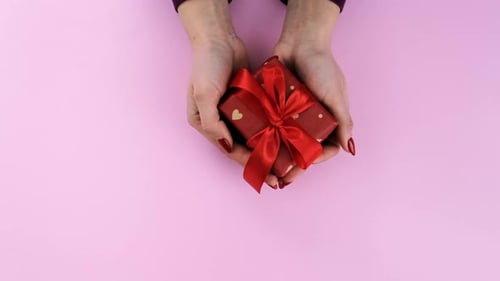 Woman Holds Wrapped Gift on Pink Background