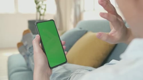 Male Video Chatting While Using Smartphone With Green Screen Display In Living Room