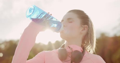 Handheld view of woman drinking water after hard workout