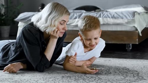 Mother and Son Use Phone Together on Floor