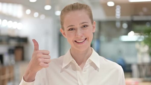 Young Woman Giving Thumbs Up in Office Setting