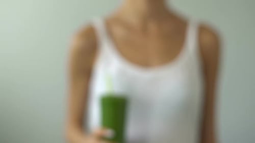 Fit Woman Holding Green Smoothie for Weight Loss Nutritious Drink for Breakfast