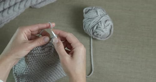 Hands Knitting Gray Wool Garment with Needles