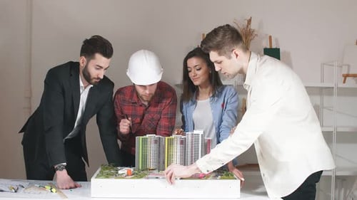 Architects Review Building Model in Modern Office
