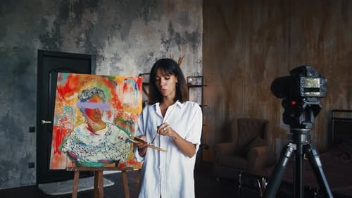 Lady Painter está dibujando un retrato sobre lienzo en estilo de arte moderno y grabando un Vídeo tutorial para