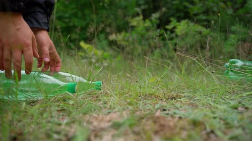 Save and rescue planet from global pollution concept. Man hand remove plastic bottles from meadow
