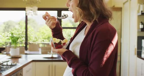 Pregnant Woman Eats Healthy Fruit in Kitchen