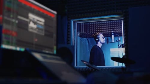 Male Rap Singer with Headphones and Sound Engineer Are Recording a New Song