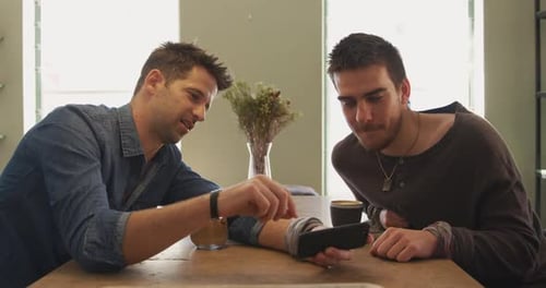 Two Young Men Using Smartphone at Table