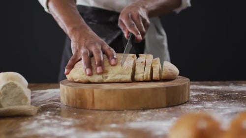 Video von Koch schneidet den Laib Brot auf schwarzem Hintergrund
