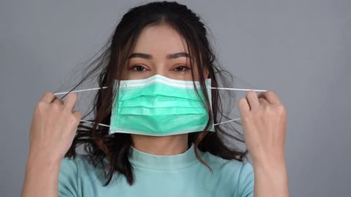 woman removes a medical mask (surgical mask) and smiling