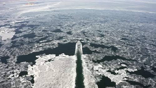 Eine Fähre zwischen Eisschollen an einem sonnigen Wintertag von einer Drohne