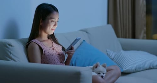 Woman with Dog Using Mobile Phone on Couch