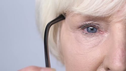 Senior Woman Puts on Eyeglasses, Macro Close Up