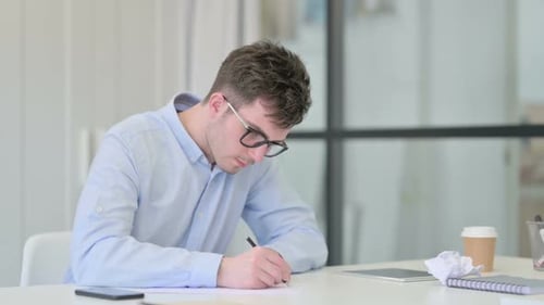 Man Writing, Crumpling Paper at Desk in Office