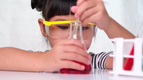 Child Scientist Stirring Red Liquid in Flask
