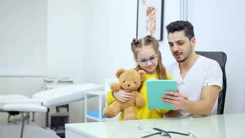 Doctor Showing Young Girl Tablet in Office