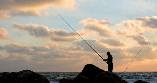 A silhouette of a fisherman at sea during sunset