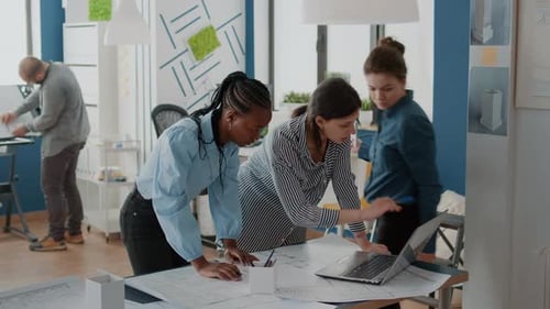 Team of Diverse Women Using Laptop to Design Blueprints Plans for Building Construction on Table