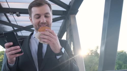 Young Manager Eating Fast Food During Lunch Break Outdoors on the Way to Work