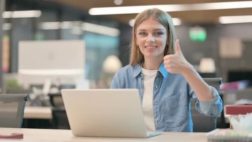 Woman Working at Laptop Gives Thumbs Up