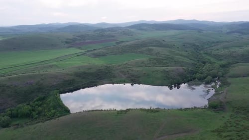 Lake with Clear Water is Located Between the Hills Greened with Grass in the Balkan Mountains Under