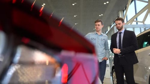 Car Salesman Explaining Features to Customer in Showroom