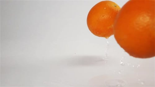 Orangen fallen und hüpfen auf grauer, nasser Oberfläche