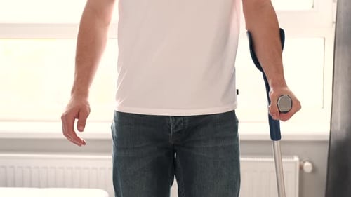 Adult Man Holding Crutch While Standing Inside