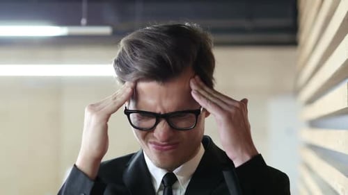 Stressed Man Massaging Temples at the Office