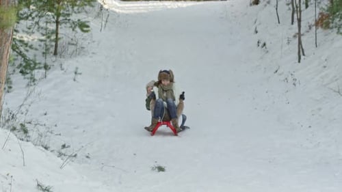 Mulher e menino em êxtase andando de trenó ladeira abaixo