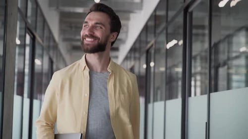 Man Smiling and Waving in Modern Office Hallway