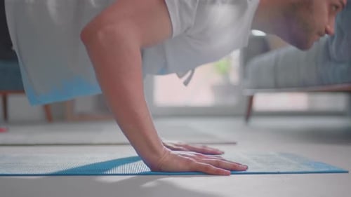 Man Doing Push-Ups on Blue Yoga Mat Indoors