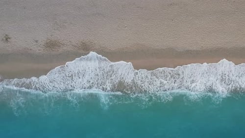Top Down View of Sandy Beach and Turquoise Sea Waves at Shore Edge