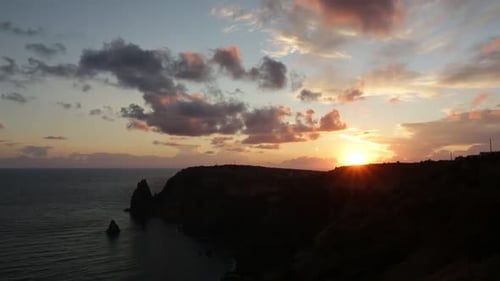 Seascape Over the Beach During Sunset with Rocky Cliff is Lit By the Warm Sunset