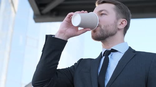 Handsome Man in Business Suit Drinking Delicious Coffee Near Business Center in USA
