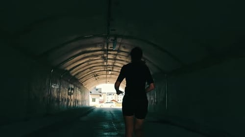 Woman Running in a Tunnel Towards the Light