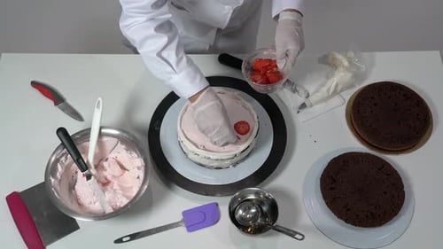 Baker decorating strawberry layer cake